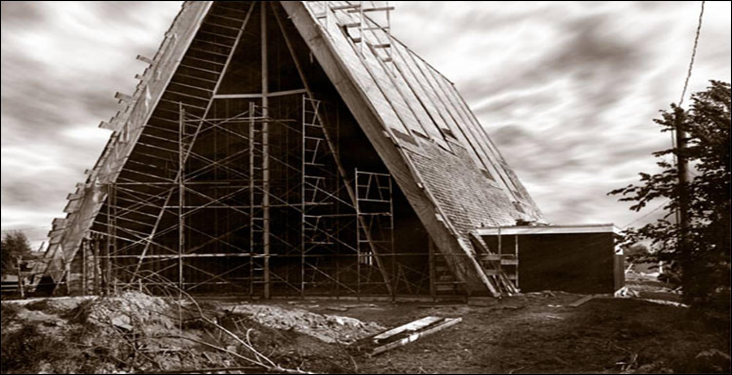 A 1964 historic photograph of the northern gable of Trinity Lutheran Church in Richmond, BC, during construction. A large steel cross has been installed at the peak of the open A-frame skeleton, surrounded by scaffolding. The sacristy wing is visible to the right, and roof decking is partially applied against a dramatic, cloudy sky.