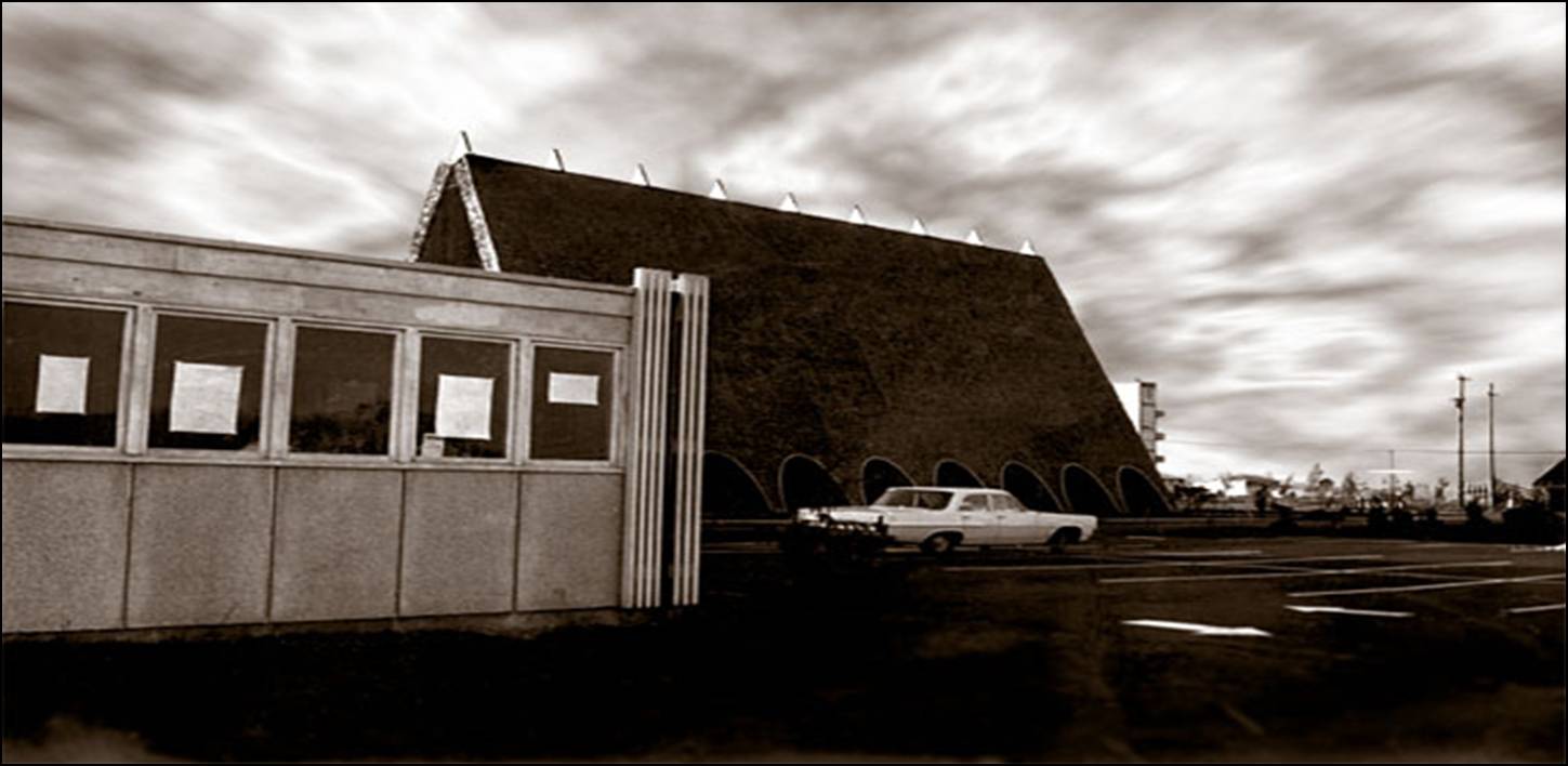 A 1964 historic photograph looking northwest at the Trinity Lutheran Church site in Richmond, BC. The original 1955 parish hall stands in the foreground, while the newly completed steep A-frame church rises in the background. The Richmond Fire Hall No. 1 training tower is visible in the extreme background. A white vintage car is parked in the lot between the structures under a dramatic, cloudy sky.
